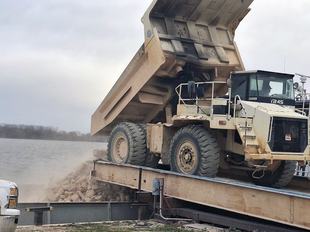 Dump Truck loading barge with rock